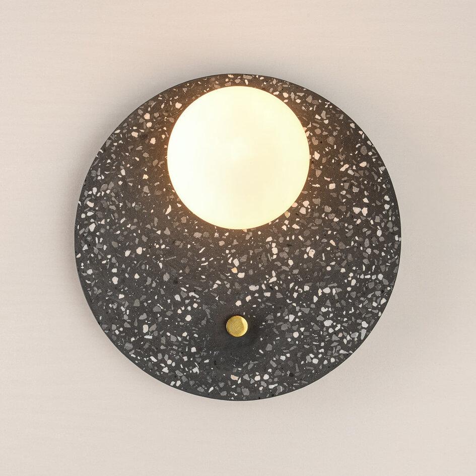 Rund vägglampa Vero av cement och mjölkvitt glas med mörkgrå terrazzolook