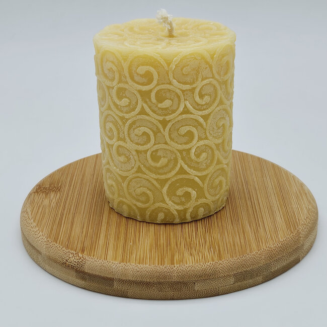 Een ronde, grote bijenwas Stompkaars met sierlijk werkje erop afgebeeld