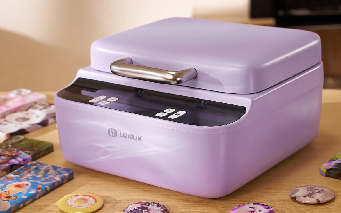 LOKLiK Phone Case Heat Press in Lavender Purple on a wooden table. Scattered around are sublimated phone cases and buttons.