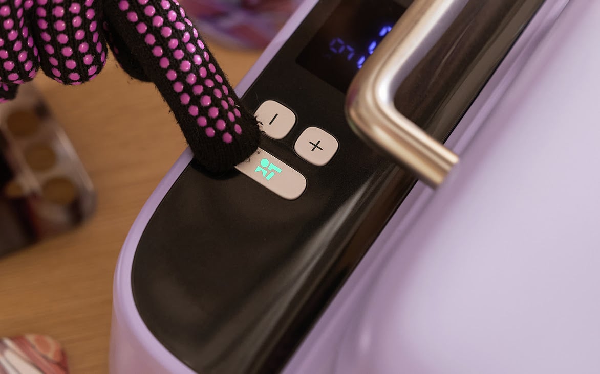 Hand wearing pink heat resistant gloves pressing the start button of a LOKLiK Phone Case Heat Press in Lavender Purple