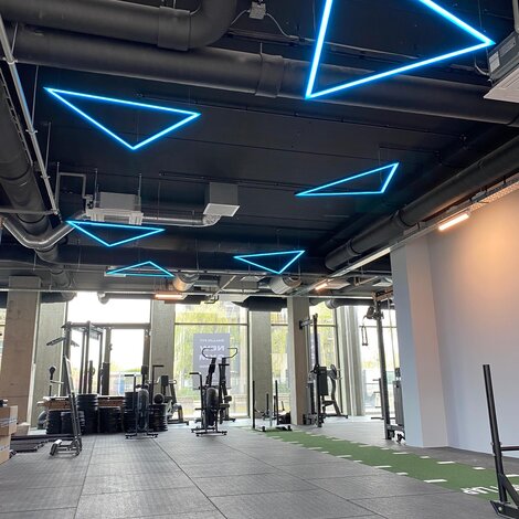 LED strips in de vorm van driehoeken zwevend aan het plafond voor een sportschool