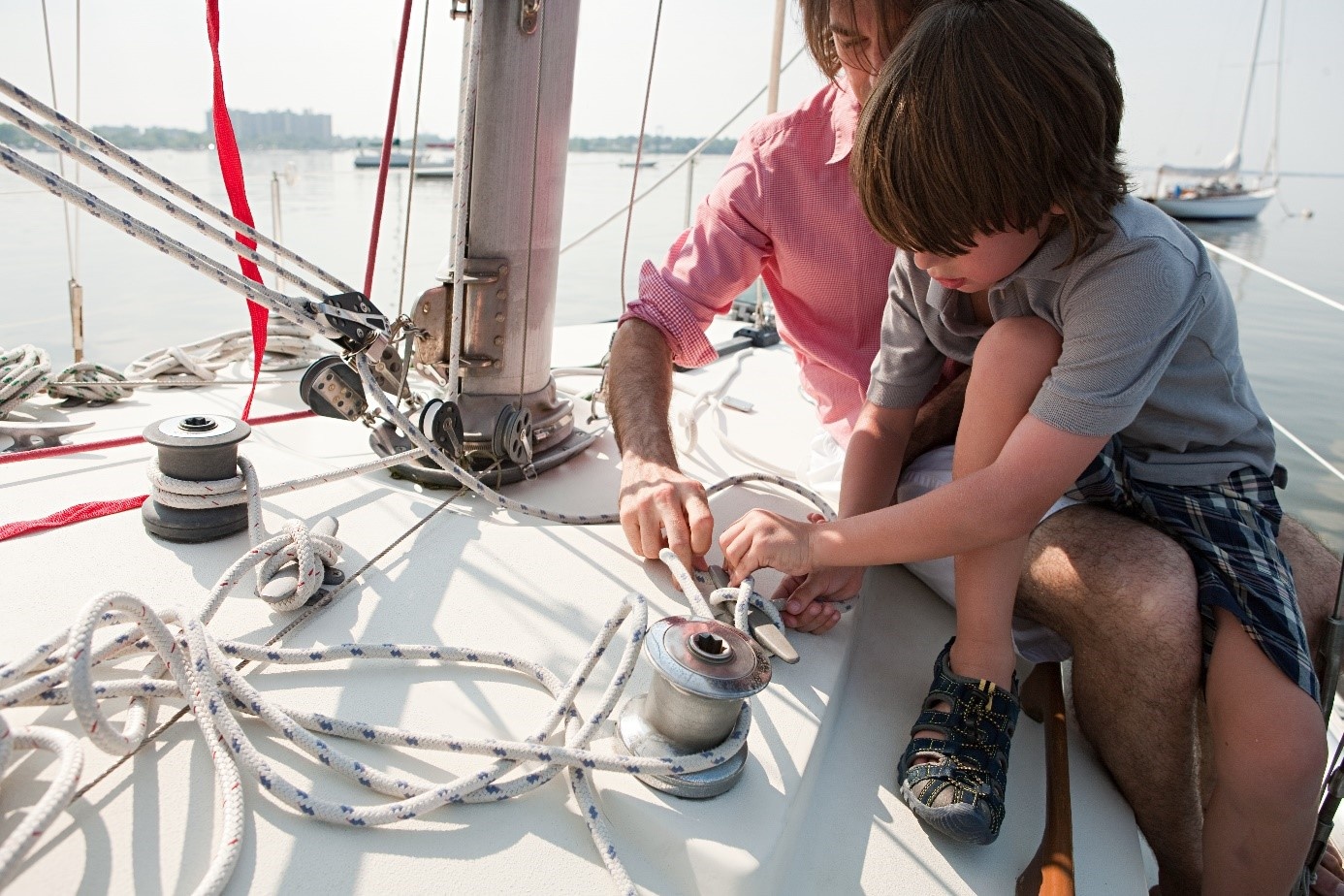 Een vader die zijn zoon laat zien hoe een scheepstouw bevestigd wordt