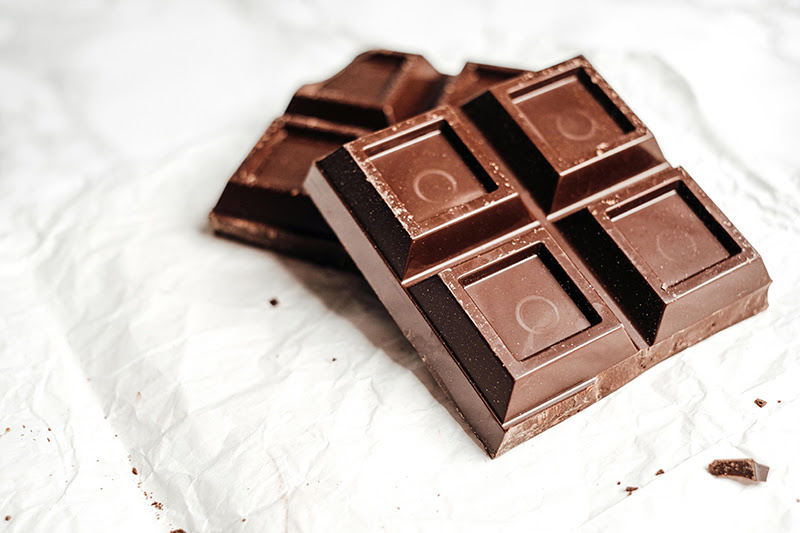 Piece of chocolate with four sqaures on a white paper background