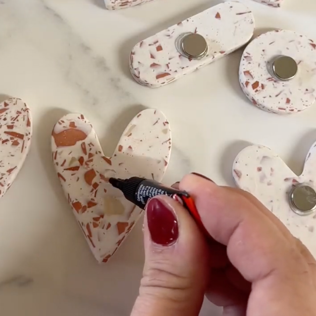Emily glues magnets to the back of the terrazzo shapes