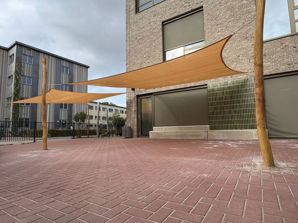 Kinderen spelen veilig in de schaduw met de schaduwdoeken van ZONZ op het schoolplein