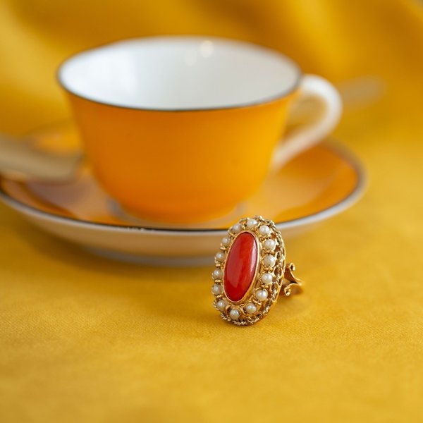 gold ring shaped as an open heart on a red coral background on Craiyon