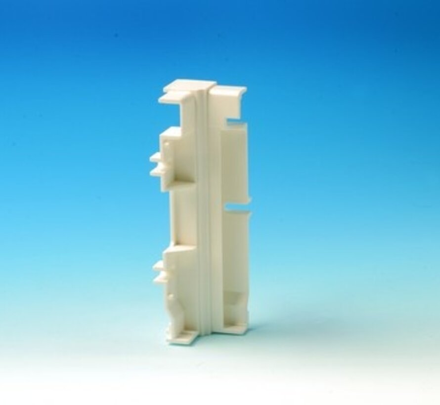 Un connecteur d'angle Elpan   (M) pour chauffage en plinthe est utilisé dans les coins pour pincer deux panneaux solidement contre le mur.