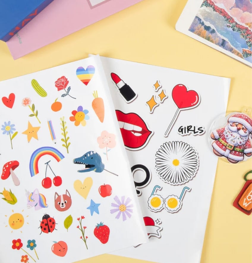 Two sheets of printed sticker sheets with an assortment of cute designs: flowers, rainbow, unicorn, strawberry,...