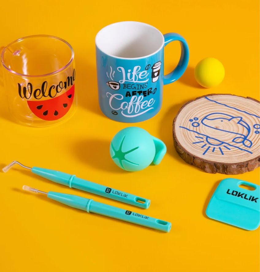 Weeding tool, a scraper and scrap collector on a vibrant light orange background. Behind these are a glass cup with a watermelon design and 'Welcome' in red and black adhesive vinyl and a blue cup with the text 'Life begins after coffee' in white and black adhesive vinyl. Next to this cup is a wooden disk with an outlined design of a whale in blue vinyl.