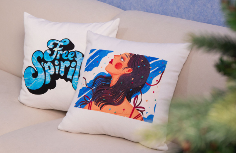 Two pillows with a heat transfer design on a sofa. The left pillow says 'Free spirit' in bold blue and black seventies style lettering. The right pillow has an illustration of a woman's face.