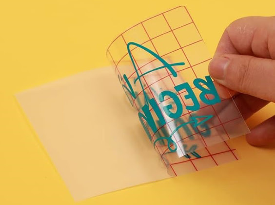 Close-up of a piece of grid transfer tape pulling a design from the PET backing.