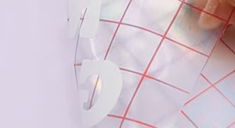 Primo piano di un pezzo di nastro transfer a griglia che estrae un design dal supporto in PET.