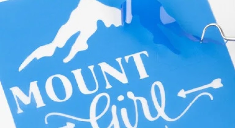 Close-up van sjabloon van een besneeuwde berg en MOUNTAIN GIRL eronder.