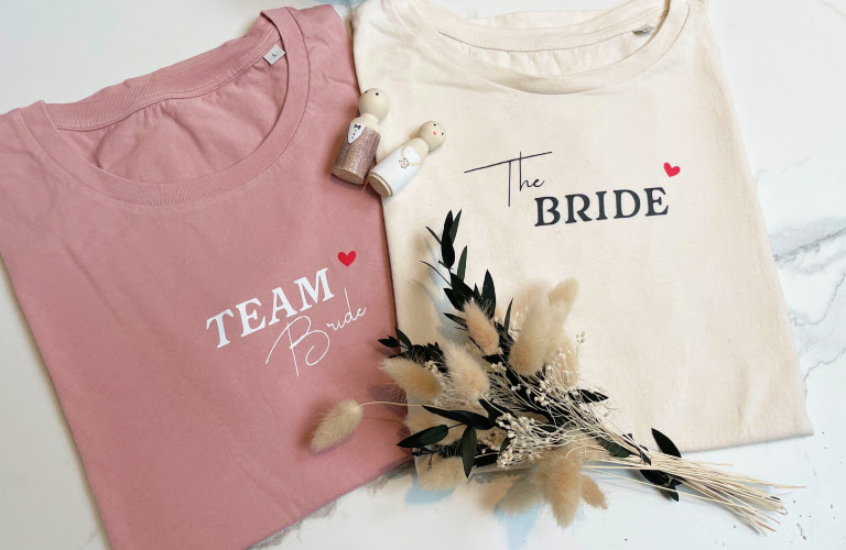 Close-up of a T-shirt in heather grey with a heat transfer print in white saying 'Team Bride' in elegant lettering.