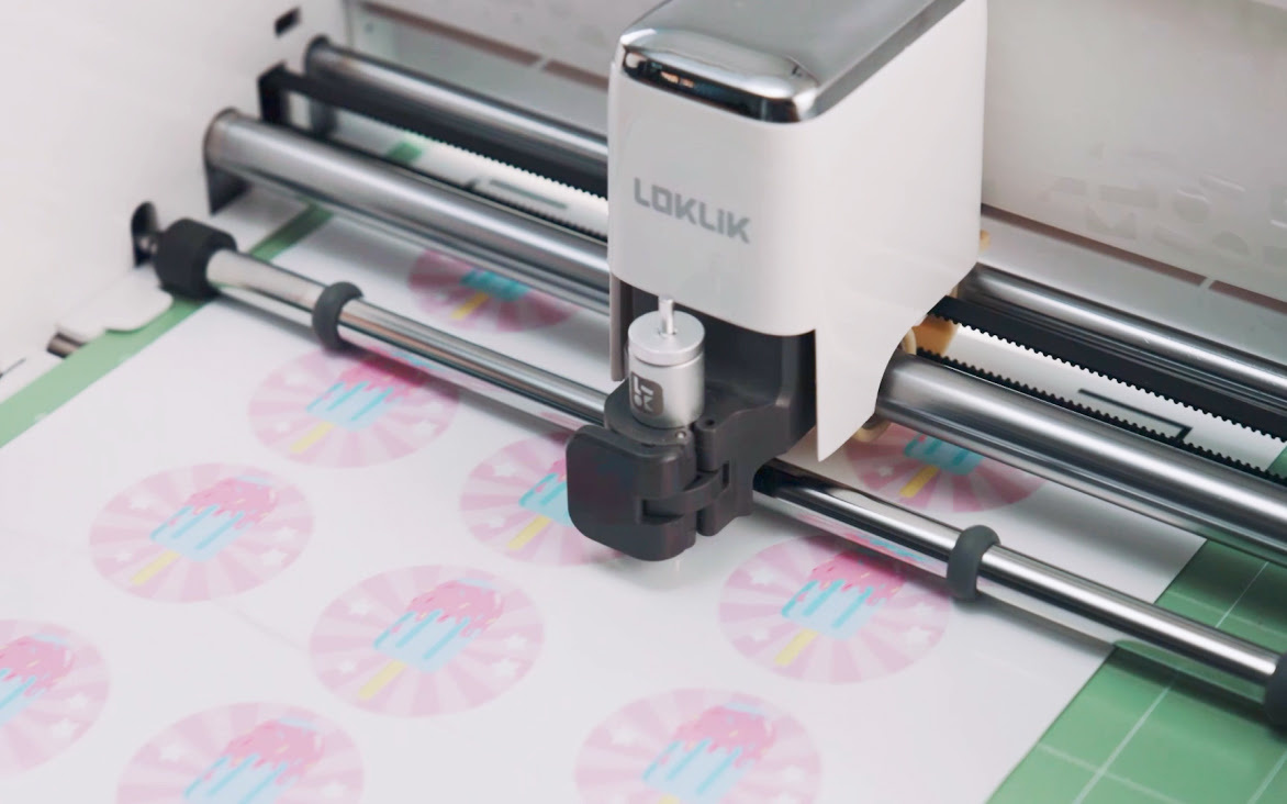 Close view the tool carriage of a LOKLiK iCraft™. The cutting machine is cutting a printed sticker sheet with the print then cut function