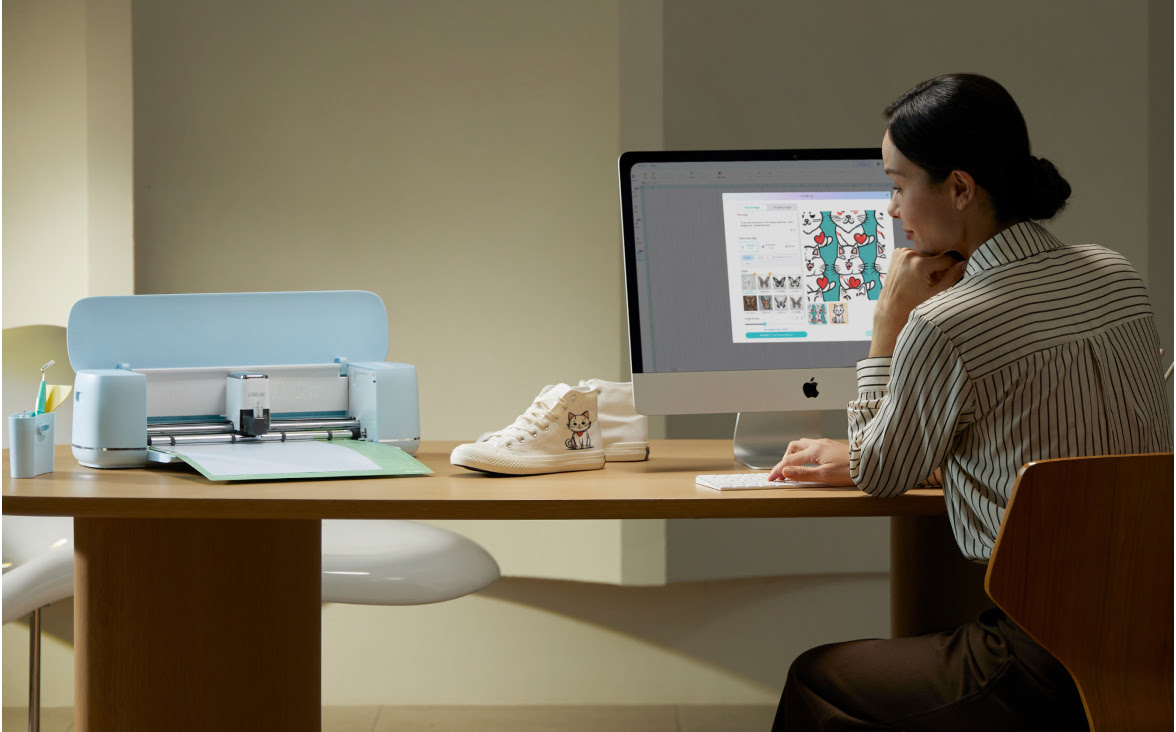 Woman sitting at a desk and computer in a slightly dim room. The computer screen showss LOKLiK IdeaStudio. There is also a LOKLiK iCraft™ in Bubble Blue on the table.
