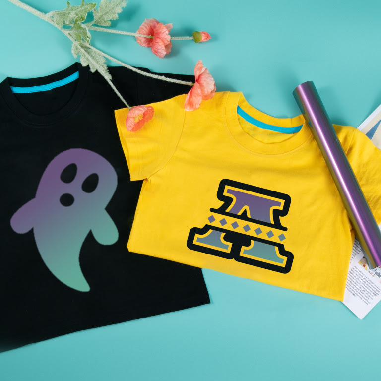Black shirt with a heat transfer vinyl design of a ghost with chameleon gold to green heat transfer vinyl and a yellow shirt with a design in the same vinyl of a capital A lying on a teal background.