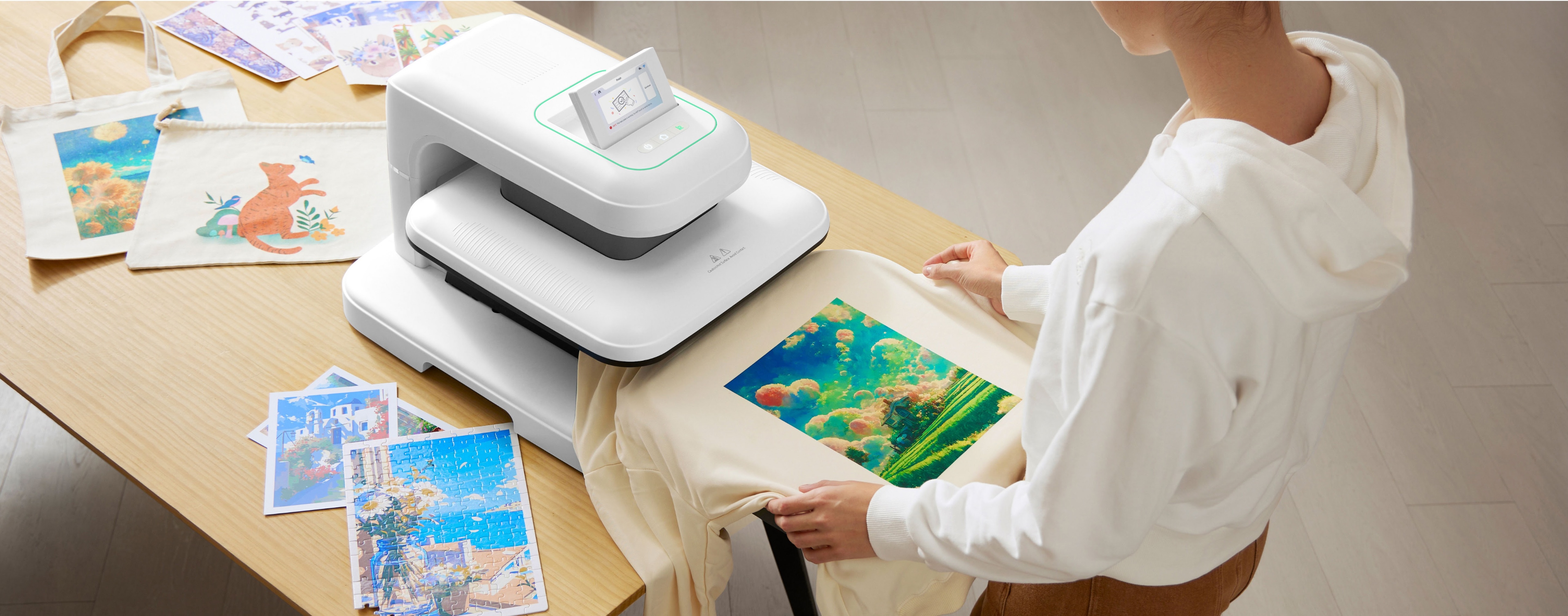 Woman placing a sweater on the ironing board of a LOKLiK ImPress™ Auto 2-Smart in Daisy White. The sweater has a DTF print of an anime-like scene with clouds and rice fields. The LOKLiK ImPress™ Auto 2-Smart is placed on a wooden table. On the table are also some DTF prints two bags and a jigsaw puzzle with a DTF print.