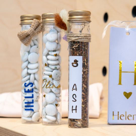 Custom baby shower favours on a wooden shelf.