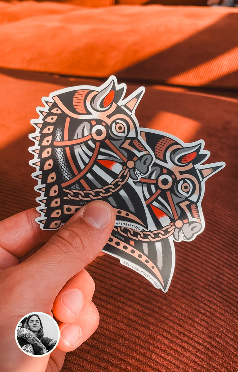 Hand holding two stickers of an illustration of an ornate horse head.