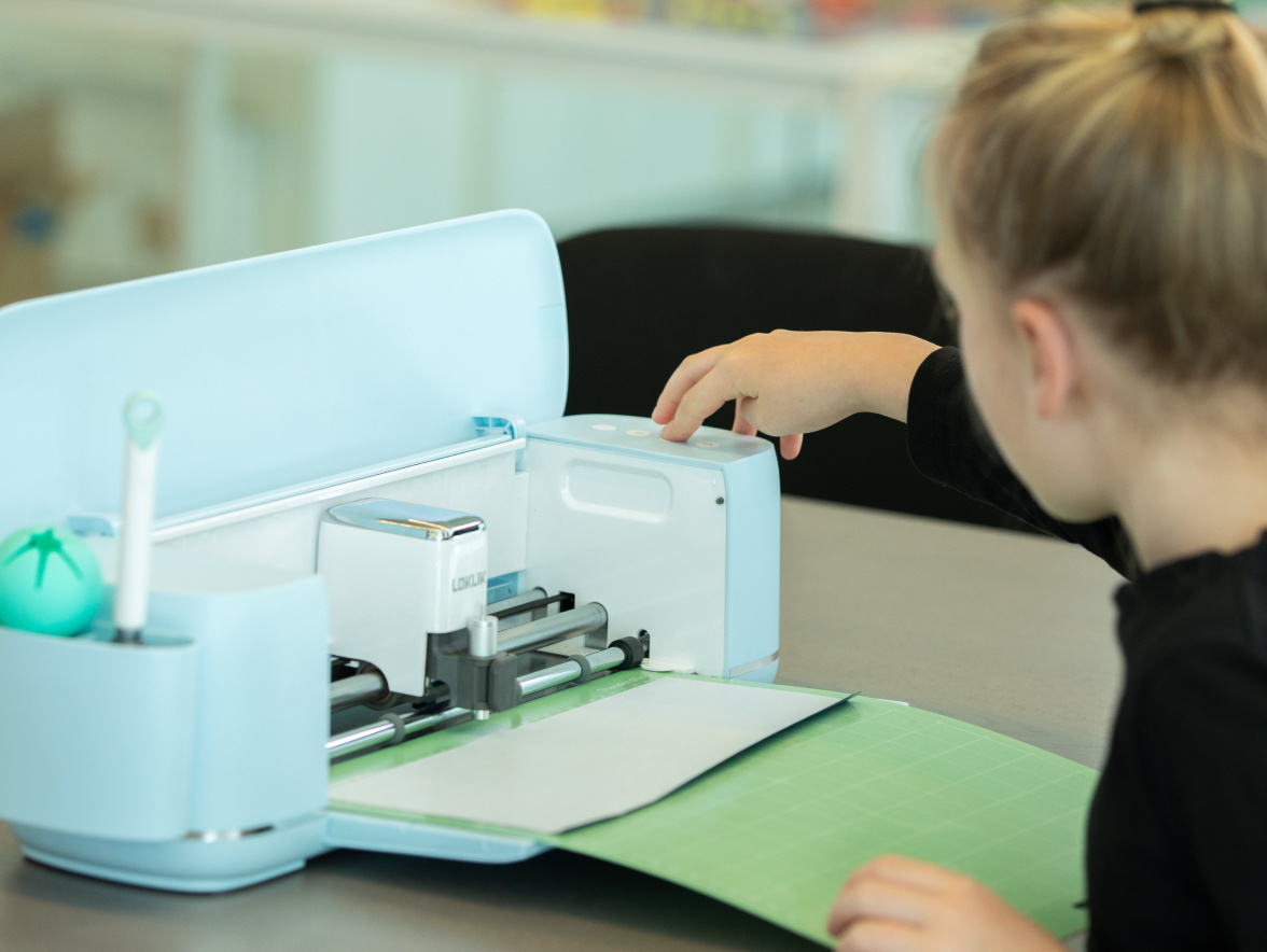 Girl in a black sweater touching the start button on a LOKLiK iCraft in Bubble Blue.