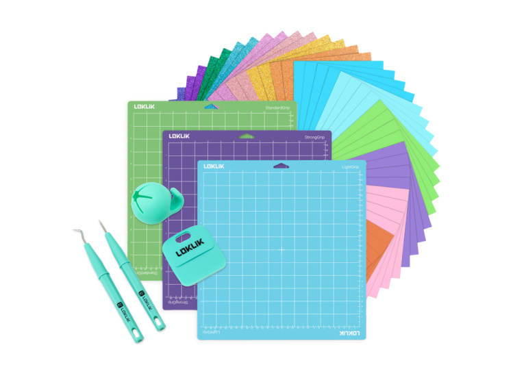 Outils de découpage, grattoir et collecteur de chutes sur 3 tapis de découpe bleu, violet et vert. Ces tapis sont posés sur un éventail de feuilles de papier cartonné de différentes couleurs.