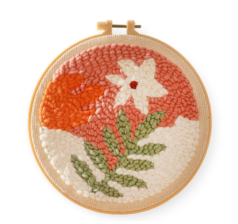 Un fiore bianco e una foglia verde su uno sfondo rosa e bianco su un tessuto da ricamo in un cerchio da ricamo.