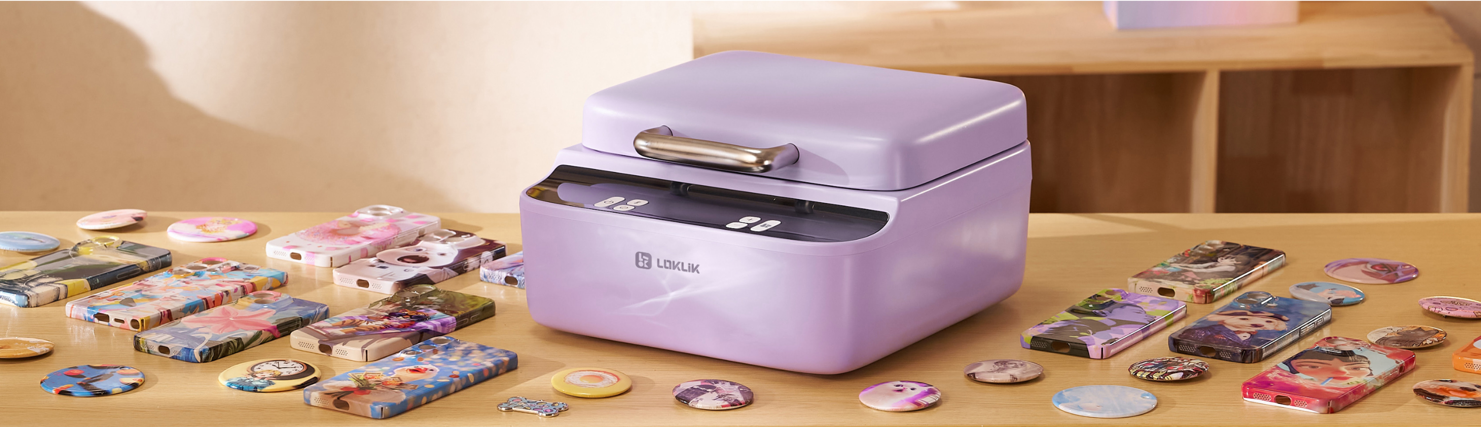 LOKLiK Phone Case Heat Press in lavendel paars op een houten tafel. De transferpers wordt omringd door voorbeelden van verschillende gepersonaliseerde telefoonhoesjes, buttons, onderzetters en dog tags.