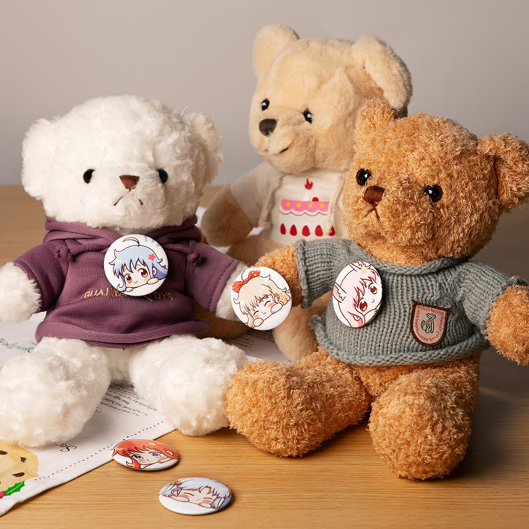 Three teddy bears in sweaters on a table. They all have a button pinned on.