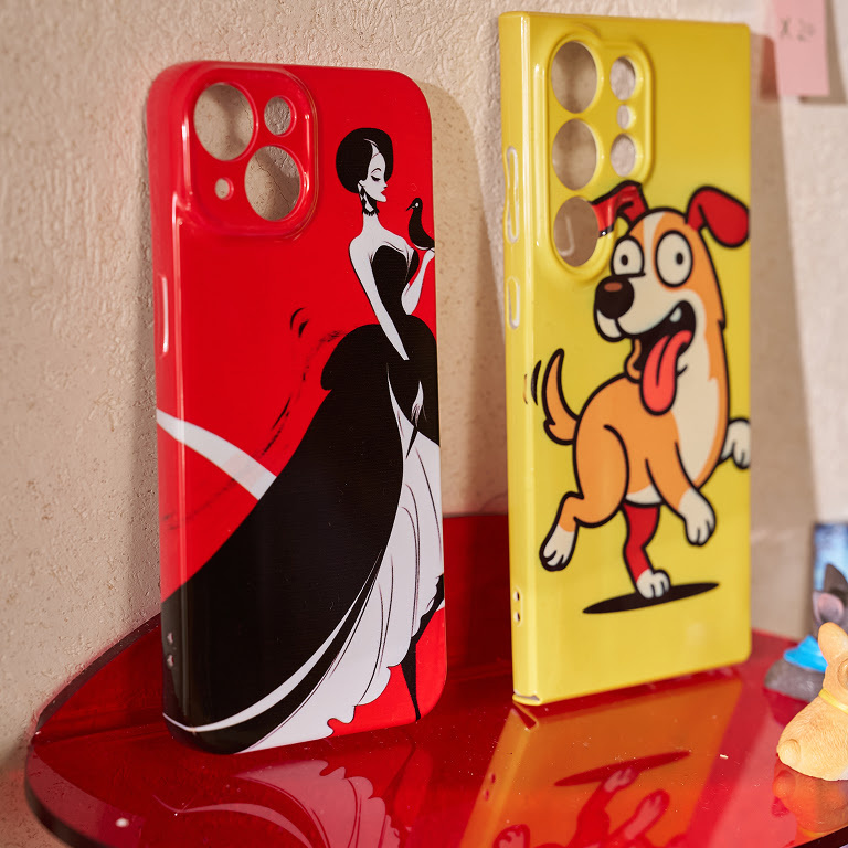 Two phone cases standing upright on a red display stand. One has an illustration of a woman in a black and white dress against a red background, the other a funny looking dog against a yellow background.
