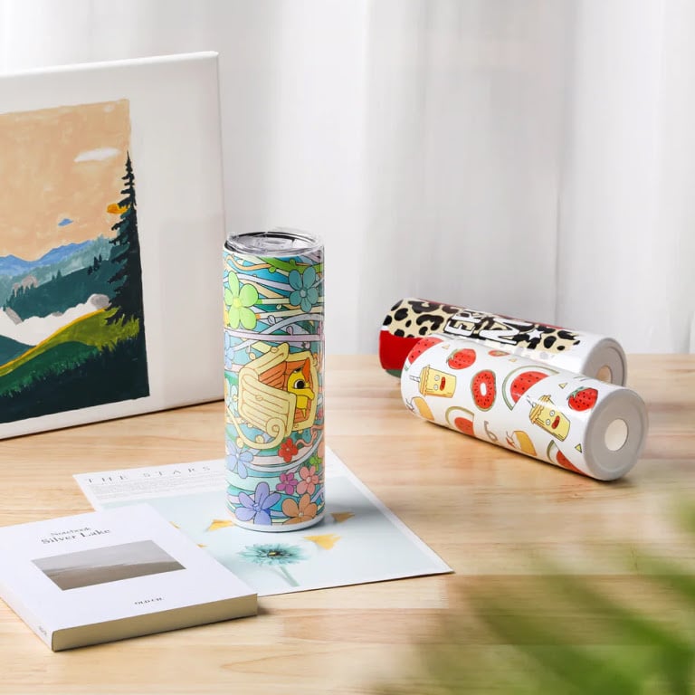 Custom printed sublimation tumblers showcasing colourful, vibrant designs on a wooden tabletop display.