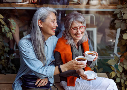 Twee vrouwen die buiten genieten van een kop koffie