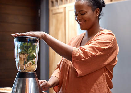 Een vrouw die een smoothie aan het maken is in een smoothie blender