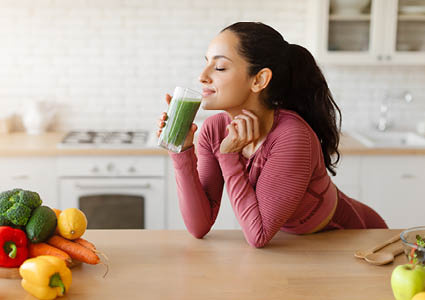 Een blije vrouw die aan het genieten is van een gezonde smoothie