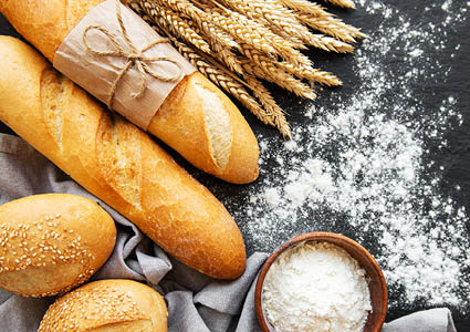 Een boven aanzicht van stokbrood, broodjes, graan en meel