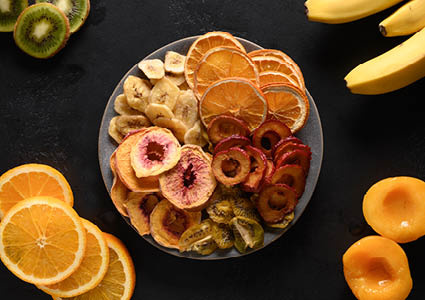Bovenaanzicht van een kommetje gevuld met gedroogd fruit, waaronder sinaasappel, appel, banaan en kiwi