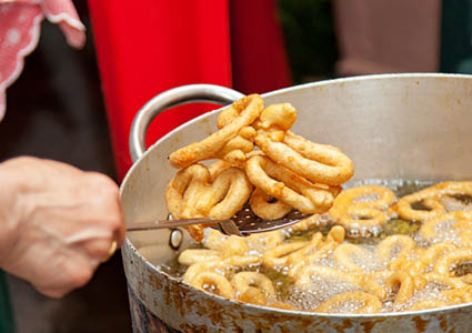 Iemand die gefrituurde visringen uit de frituurpan haalt