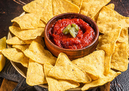 Een bord gevuld met nachos en in het midden staat een schaaltje gevuld met salsadip