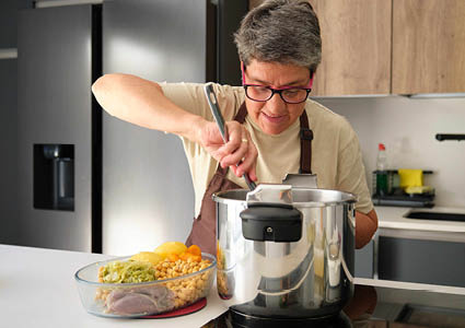 Een mevrouw die aan het koken is met een snelkookpan