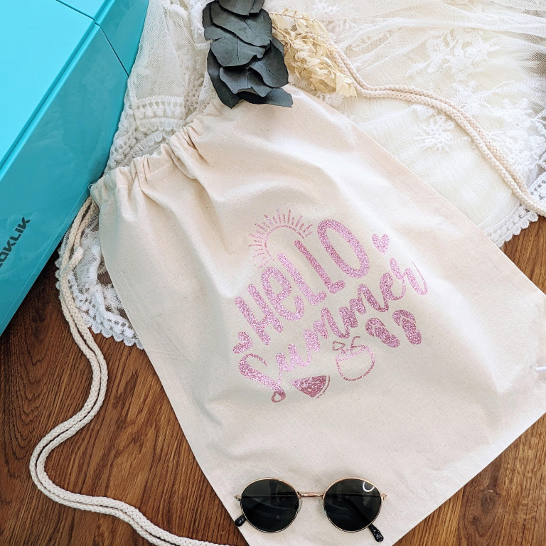 Drawstring bag with a heat transfer print of the text 'Hello summer' made with LOKLiK Glitter Pink Heat Transfer Vinyl.