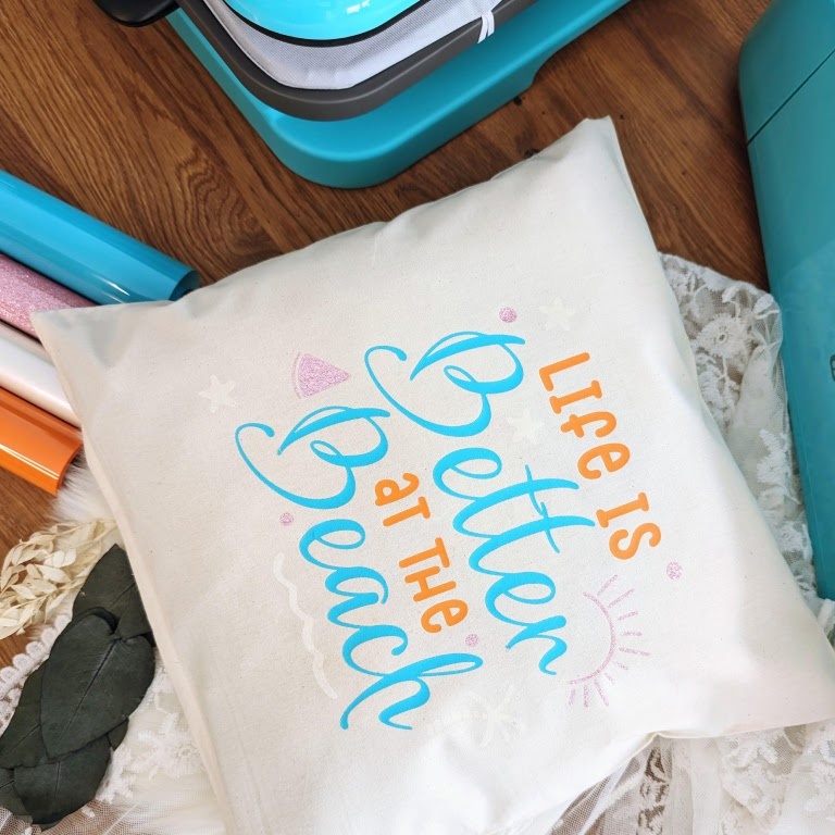 White pillow with a heat transfer print saying 'Life is better at the beach.'