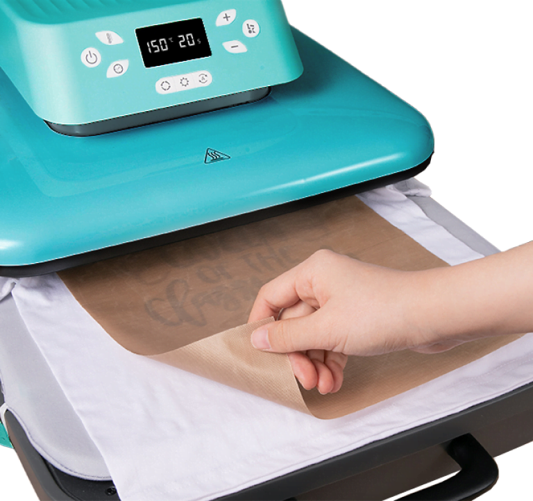 LOKLiK Auto Heat Press with the drawer pulled out. A hand is reaching out to peel off a teflon sheet from a white shirt.