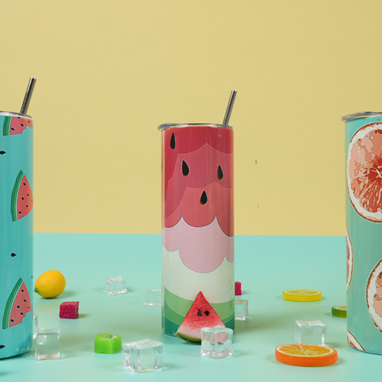 Three tumblers on a mint green table against a yellow background. They have sublimation designs of water melons and grapefruit.