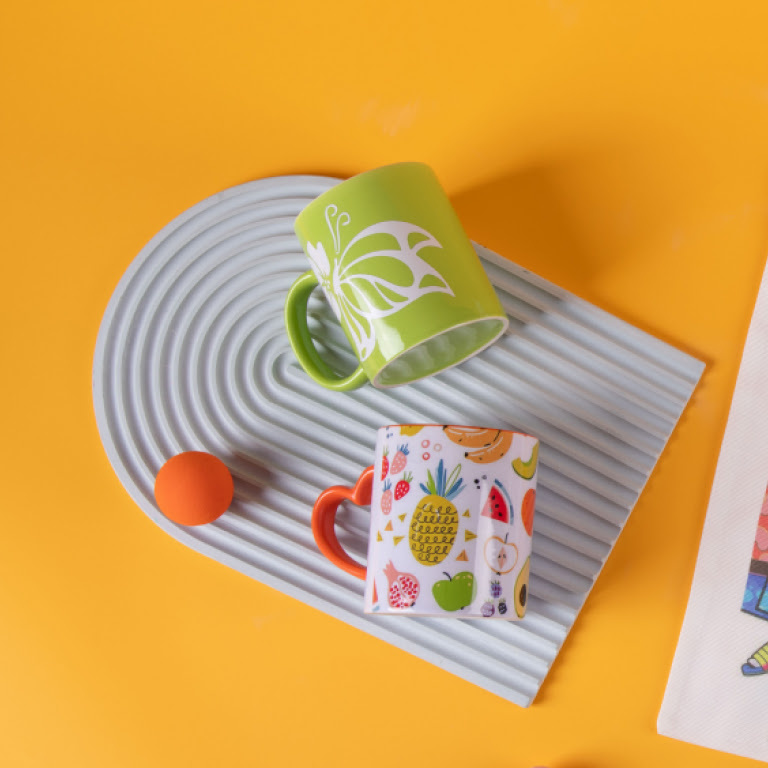 Top down view of two mugs on an orange background.