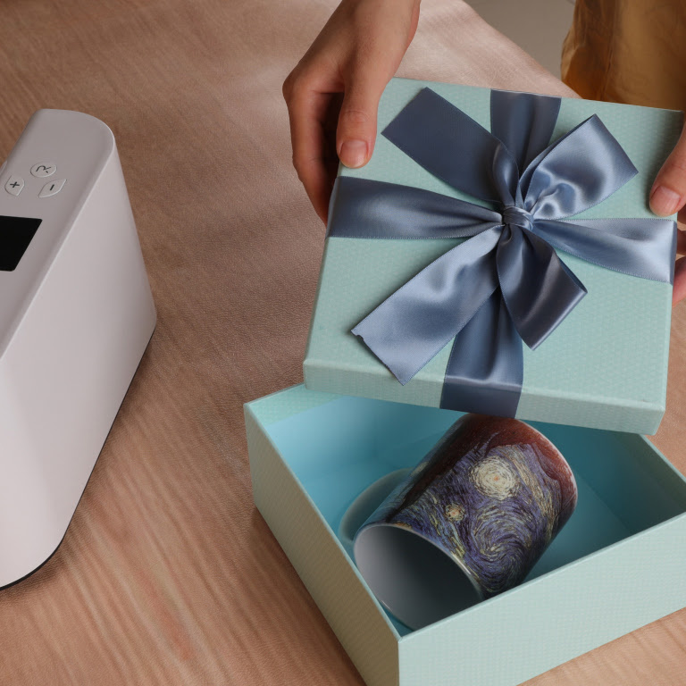 Woman opening a box with a mug which has a sublimation print of Van Gogh's Starry Night.