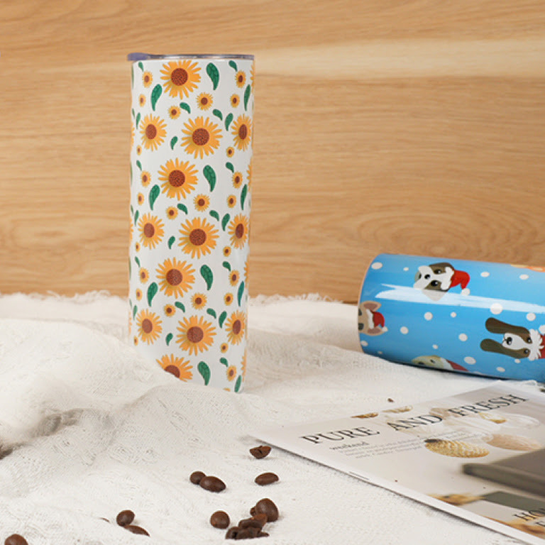 Tumbler with sunflower pattern sublimation print against a wooden background.