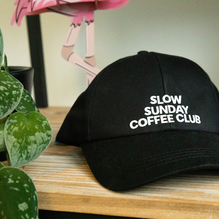 A black cap with the words 'slow sundnay coffee club' ironed on in white heat transfer vinyl.