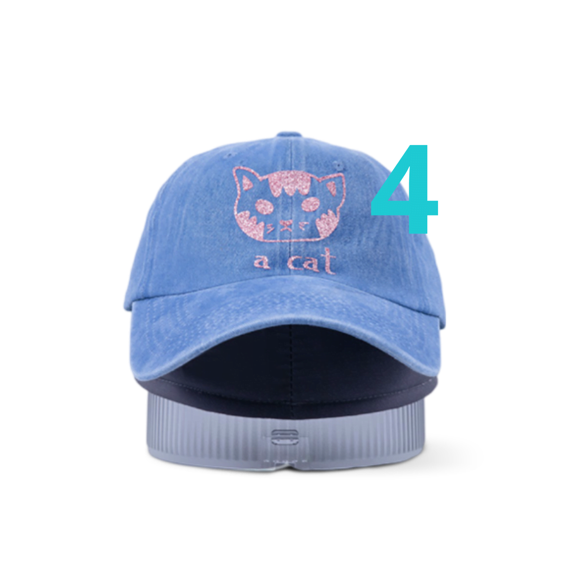 Frontal view of a blue cap on the heat press mat and pressing lit. It has a design of a cat and the words 'a cat' beneath it in glitter pink heat transfer  vinyl.