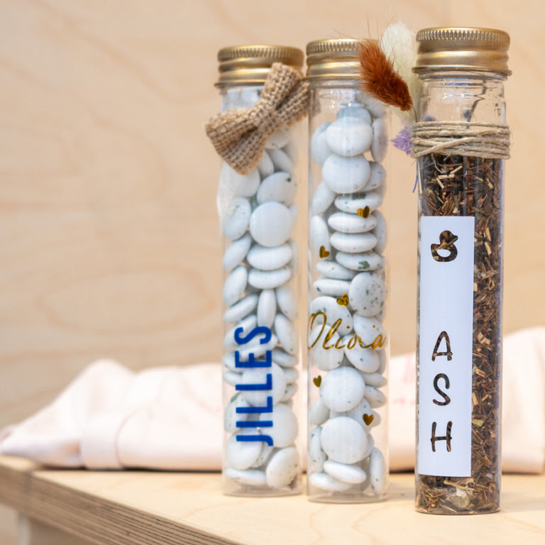 Three plastic tubes with chocolates to celebrate the birth of a child. They have the names Jilles, Olivia and Ash on them in vinyl.