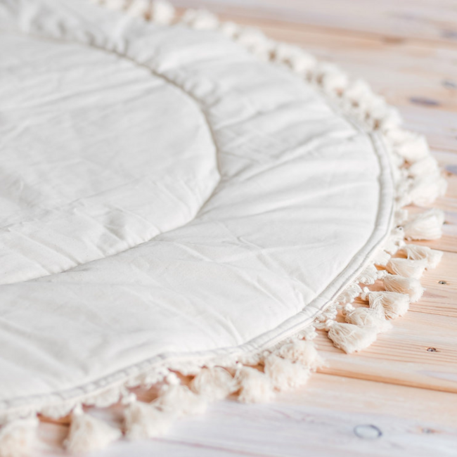 Speelkleed in boho stijl met kwastjes in ecru – zacht, stijlvol en perfect voor de babykamer